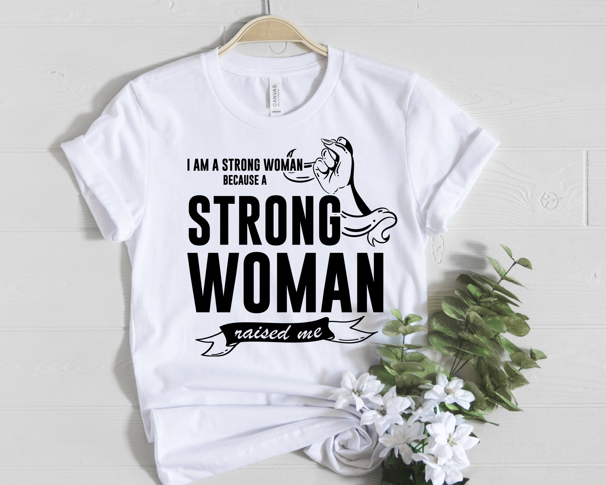 White and black t-shirt stating: I am a Strong Woman because Strong Woman raised me!